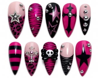 Puede incluir: Un conjunto de diez uñas postizas en forma de almendra con una paleta de colores rosa y negro. Los diseños incluyen estampado de leopardo, rayas de cebra, rayas horizontales, estrellas, cruces, una calavera con lazo y esferas metálicas plateadas.