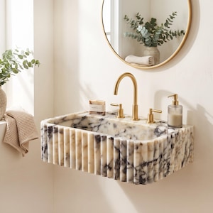 Calacatta Viola fluted marble sink in a luxury bathroom, featuring dramatic purple veining, handcrafted stone details and a modern wall-mounted design.