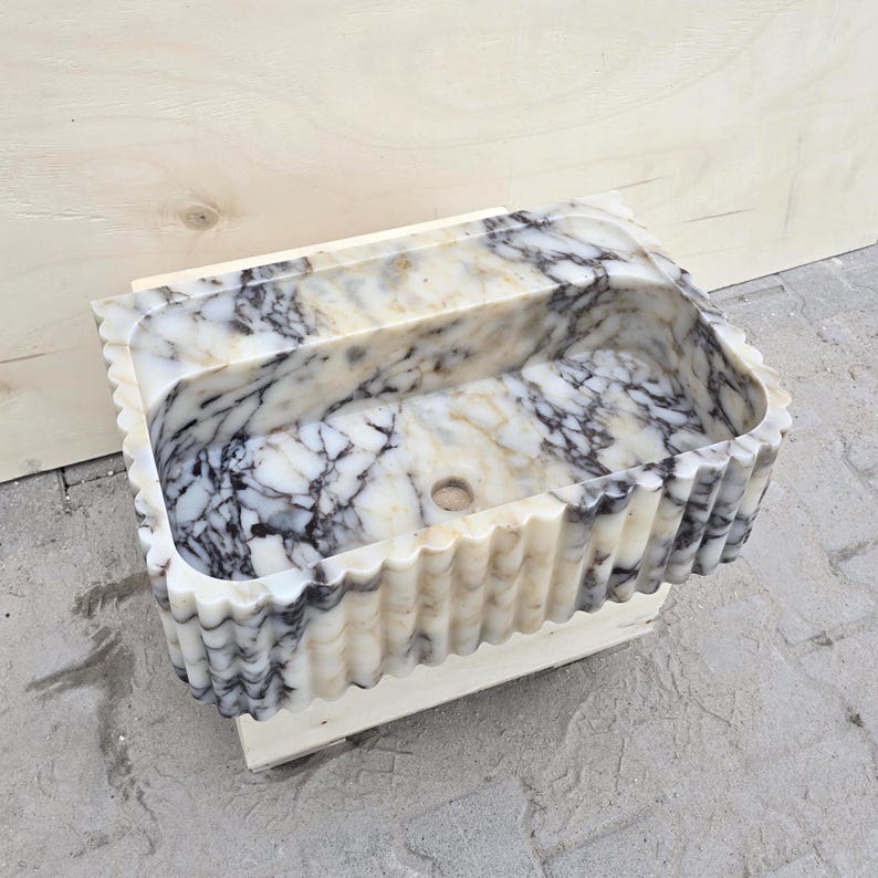 Handmade Calacatta Viola stone sink with fluted marble front, cream background and bold purple veining, designed for a modern bathroom vanity.