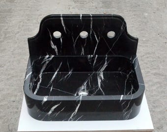 May include: A black marble sink with a white veined pattern. The sink has a rectangular shape with rounded edges and three holes in the backsplash.