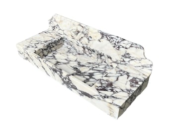 May include: A rectangular marble sink with a white and black veined pattern. The sink has a built-in basin and a decorative edge. The overall design is modern and elegant, suitable for a bathroom.