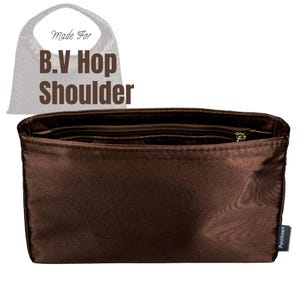 May include: A dark brown rectangular bag organiser insert with a zippered top compartment and an open main section. The text Made For B.V Hop Shoulder is visible above the insert. A small black fabric tag with the brand name Purzlnzert is attached.