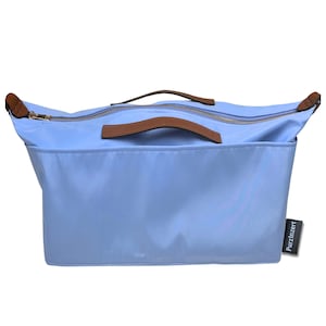 May include: A light blue tote bag with brown leather handles and trim. The bag has a zipper closure and a rectangular shape. The brand name "Purzinzert" is printed on a small tag on the side.