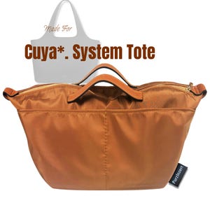May include: A copper-coloured nylon bag organiser with two top handles, a gold-tone zip closure, and an external pocket. The text "Made For Cuya*. System Tote" appears above, and a black tag with the white text "Purzlnzert" is attached.
