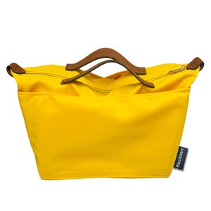 May include: A bright yellow tote bag with brown leather handles and a zipper closure. The bag has a rectangular shape and a tag that reads "PurzInzert". The handles are curved and attached to the top of the bag.