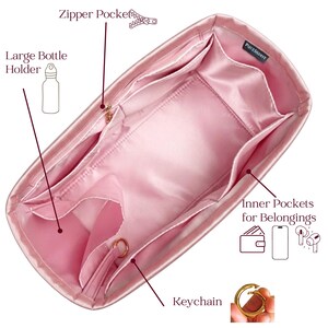 May include: Pink satin handbag organizer with multiple pockets, including a large bottle holder, zipper pocket, and inner pockets for belongings. Features a keychain ring. The organizer is designed to keep items organized.