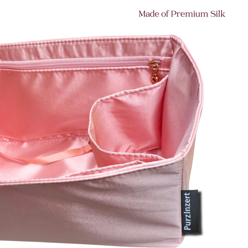 May include: A close-up of a pink silk organizer with multiple compartments and a zippered pocket. The organizer has a satin finish and a gold zipper pull. The text "Made of Premium Silk" is visible at the top.