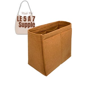 Puede incluir: Un organizador de bolso de fieltro marrón con múltiples compartimentos y bolsillos. El organizador está etiquetado como "Made For LE 5 A 7 Supple".