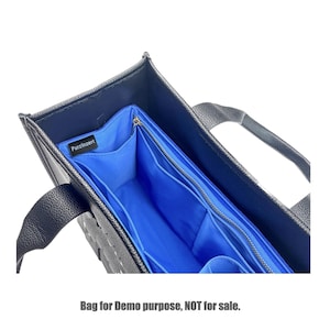Può includere: Borsa tote nera con un organizer interno blu. L'organizer ha più scomparti e una chiusura a cerniera. La borsa ha due manici e il testo "Purzinzert" è visibile.