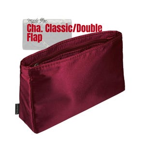 Puede incluir: Un organizador de bolso de color burdeos con cremallera en la parte superior. El organizador es rectangular y está hecho de un material liso similar al satén. El texto de la imagen dice "Made For Cha. Classic/Double Flap".