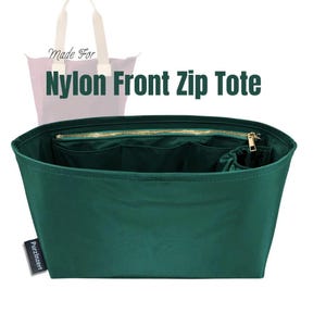 Może przedstawiać: Ciemnozielona torba Nylon Front Zip Tote ze złotym zamkiem błyskawicznym i wieloma wewnętrznymi kieszeniami. Torba ma prostokątny kształt i małą etykietę z napisem "Purzinzert". Tekst "Made For" znajduje się powyżej.