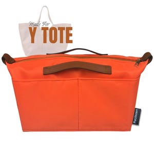 Könnte beinhalten: Hellorangefarbener Organizer für eine Tragetasche mit braunen Ledergriffen und Reißverschlusszippern. Der Organizer hat mehrere Taschen und den Text "Made For Y TOTE". Die Tasche ist für den Einsatz in einer Tragetasche konzipiert.