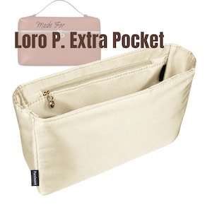 Peut inclure: Un organisateur de sac rectangulaire de couleur crème doté de plusieurs compartiments intérieurs, d'une poche zippée avec une tirette circulaire dorée et d'une petite étiquette en tissu noir marquée Purzinzert. Le texte Made For Loro P. Extra Pocket est visible.