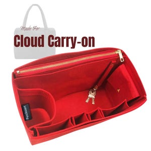 Puede incluir: Un organizador de bolso de fieltro rojo con múltiples compartimentos y una cremallera dorada. El organizador tiene un pequeño bolsillo con cierre de botón a presión y un llavero con llaves. El texto "Made For Cloud Carry-on" es visible.