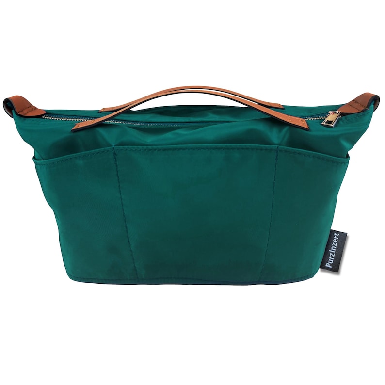 May include: A teal handbag with brown leather handles and accents. The bag has a zipper closure and multiple exterior pockets. The brand name "Purzinzert" is visible on a small tag.