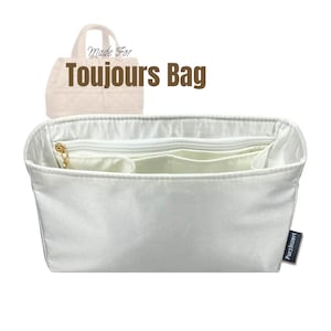 May include: A white bag organizer with multiple compartments and a zippered pocket. The text "Made For Toujours Bag" is displayed above the organizer. A small tag with the text "Purzinzert" is on the right side.