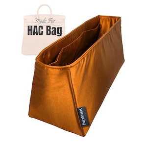 Puede incluir: Un organizador de bolso de color bronce con múltiples bolsillos interiores. El organizador es rectangular con forma trapezoidal y una etiqueta que dice "PurzInzert". Un gráfico de bolso blanco con el texto "Made For HAC Bag" está en el fondo.