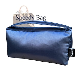 May include: A dark blue, rectangular, padded bag with a handle. The bag is made of a soft, silky material and has a small label that says "Purzzlnzert". The bag is designed to fit inside a "Speedy Bag" handbag.