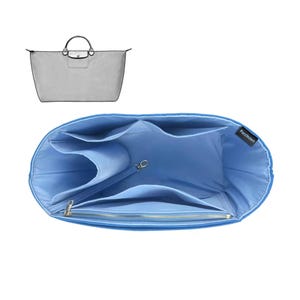 May include: A light blue bag organiser with multiple compartments and a zipped pocket. The organiser is designed to fit inside a tote bag, with a silver-coloured clasp and the brand name "Purzinzert" visible.