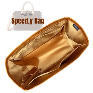 May include: Gold-colored bag organizer with multiple pockets and compartments. The organizer is designed to fit inside a Speed.y Bag, as indicated by the text in the image. Features include a zippered pocket and a key ring.