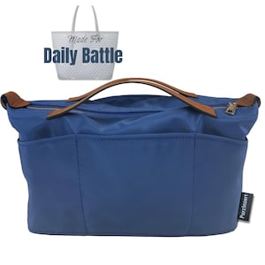 May include: A blue tote bag organizer with brown leather handles and a zipper closure. The bag has multiple pockets and the text "Made For Daily Battle" is visible in the background.