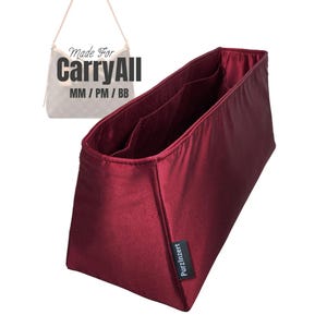 May include: A burgundy fabric bag organiser with multiple interior pockets. The organiser is rectangular with a trapezoidal shape and features the text "PurzInzert" on a small black tag. The image also includes the text "Made For CarryAll MM/PM/BB".