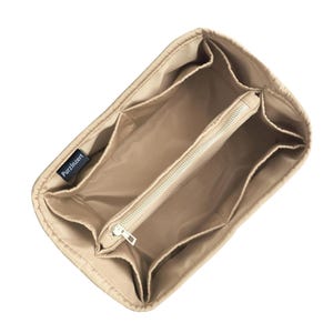 May include: Beige handbag organiser with multiple compartments and a zipped centre section. The organiser has several pockets of varying sizes and the brand name "PurzInzert" is visible on a small label.