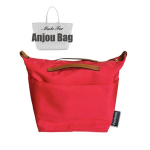 Puede incluir: Un organizador de bolso rojo brillante con asas y ribetes de cuero marrón. El bolso tiene múltiples bolsillos y un cierre de cremallera. El texto "Made For Anjou Bag" está encima del bolso. Una pequeña etiqueta con "PurzInzert" está en el lateral.