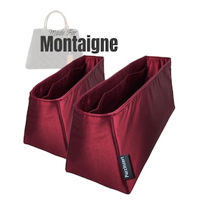 Könnte beinhalten: Zwei weinrote Handtaschen-Organizer mit mehreren Innentaschen. Die Organizer bestehen aus einem glänzenden, satinartigen Material. Der Text "Made For Montaigne" befindet sich über den Organisatoren. Ein kleines schwarzes Etikett mit dem Text "PurzInzert" befindet sich auf einem Organizer.