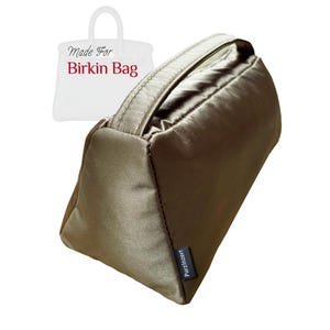 May include: An olive-green satin bag with a handle, designed for a Birkin bag. The bag is rectangular with a handle on top. The text "Made For Birkin Bag" is visible in the background, along with the brand name "PurzInzert".