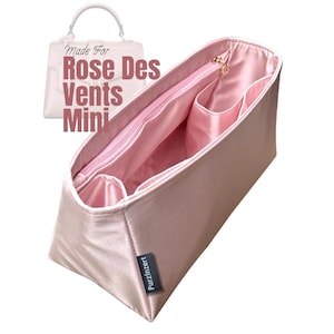May include: A pink satin bag organizer with multiple pockets and a zippered compartment. The organizer has a rectangular shape and a small black tag that says "PurzInzert". The text "Made For Rose Des Vents Mini" is in the background.