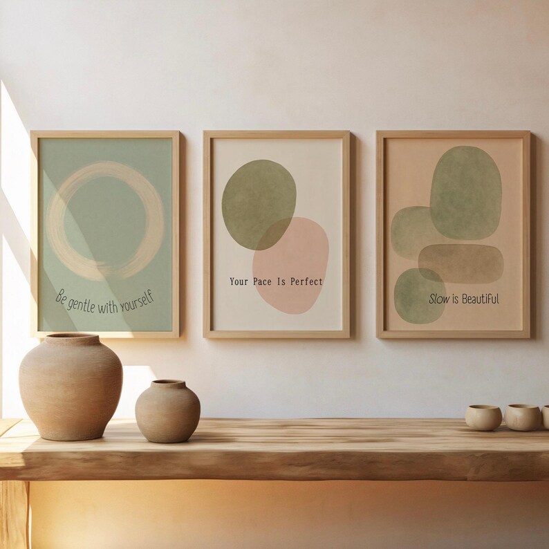 May include: Three framed art prints with abstract designs and inspirational quotes. The prints feature soft colors like green, pink, and beige. The text on the prints reads: "Be gentle with yourself", "Your Pace Is Perfect", and "Slow is Beautiful".