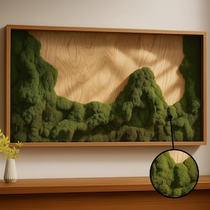 May include: A rectangular wall art piece featuring a light-colored wood panel with a natural grain pattern, partially covered by textured, deep green preserved moss. The artwork is enclosed in a thin, light-toned wooden frame.