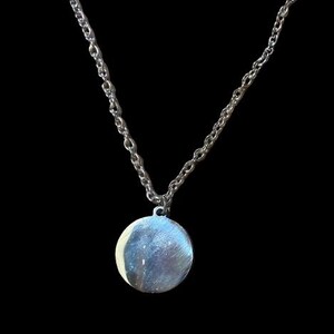 Peut inclure: Un collier en cha&icirc;ne argent avec un pendentif rond en argent.