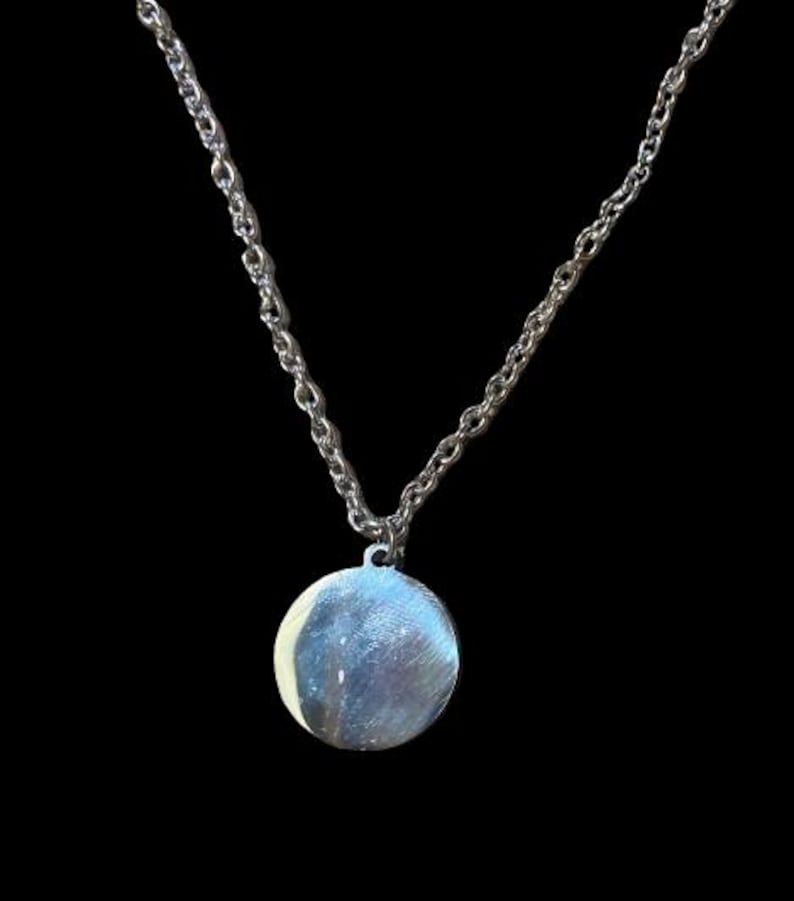 Peut inclure: Un collier en cha&icirc;ne argent avec un pendentif rond en argent.