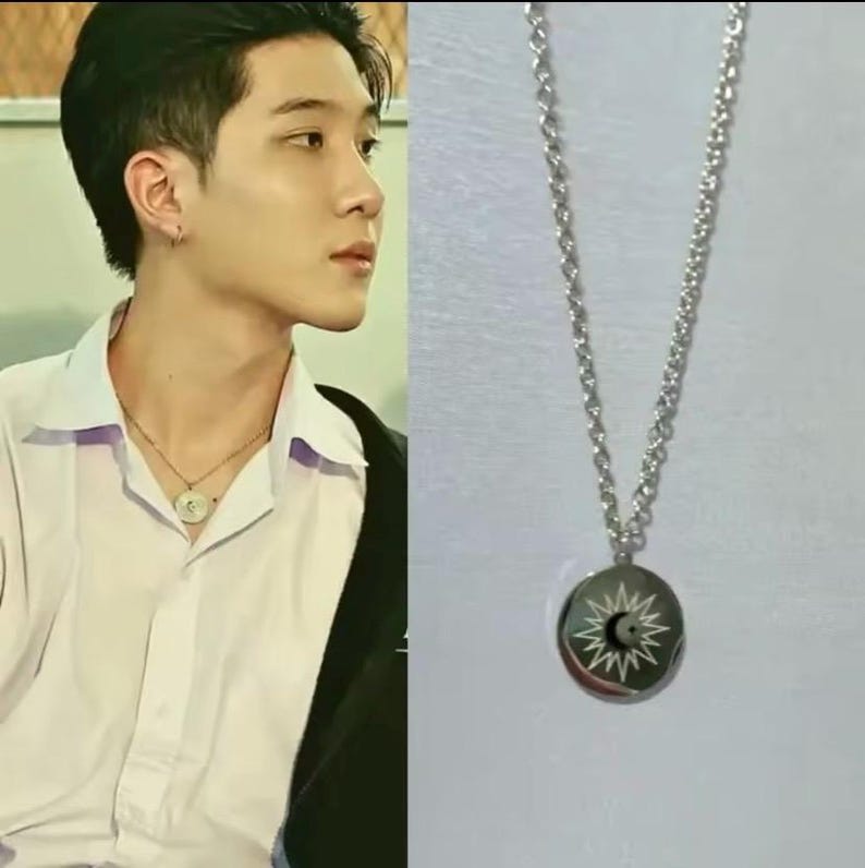 Peut inclure: Un collier en cha&icirc;ne argent avec un pendentif rond repr&eacute;sentant un soleil et une lune.