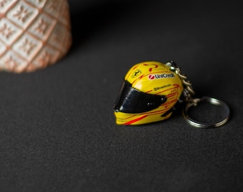 May include: A yellow and black racing helmet keychain with the word "UniCredit" printed on it.