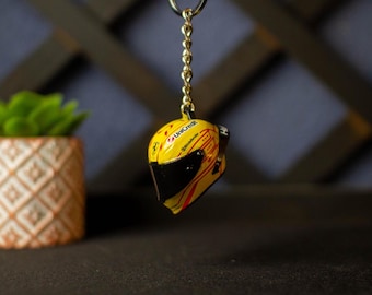 May include: A yellow and red racing helmet keychain with a black visor and the text "UniCredit" on the side.