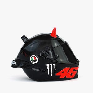 May include: Black motorcycle helmet with a red number 46, a red spike on top, and a Monster Energy logo. The helmet has a clear visor and a white Agu logo.