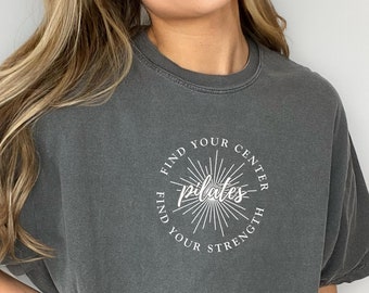 May include: An oversized grey t-shirt with a white circle graphic that says "Find Your Centre Find Your Strength Pilates".