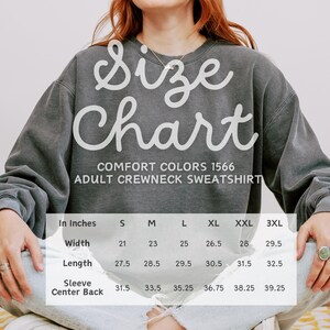 May include: Size chart for adult crewneck sweatshirts in Comfort Colors 1566. The chart shows measurements in inches for width, length, sleeve, and center back. Sizes range from S to 3XL.