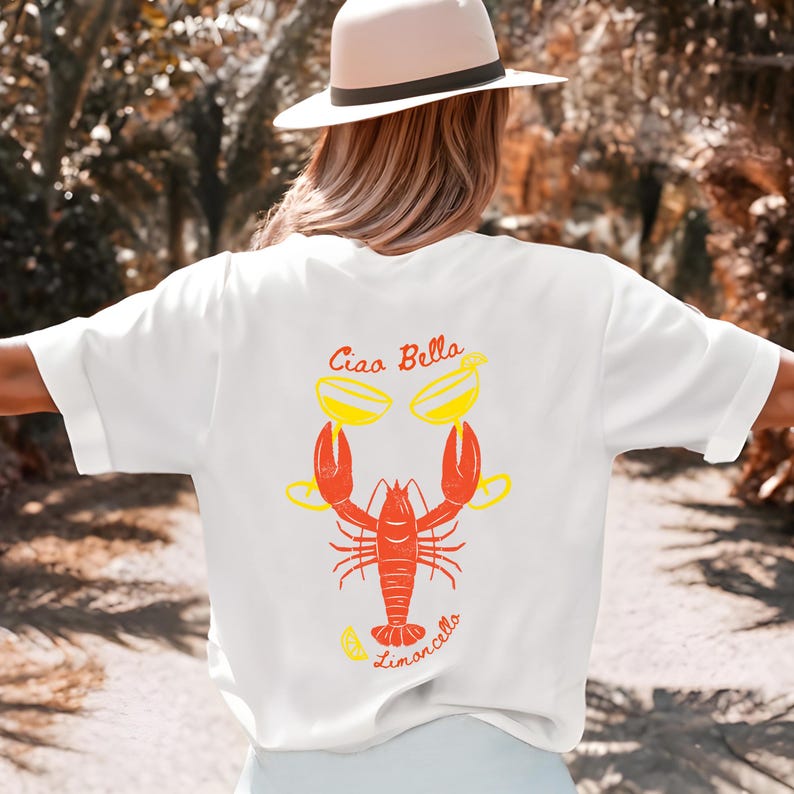 May include: White t-shirt with a red lobster holding two yellow cocktails and the text "Ciao Bella Limoncello" printed on the back.