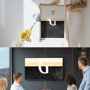 May include: A black and white abstract art print with a gold harp and the letter "G" in white. The print is framed in a light wood frame and is hanging on a wall.