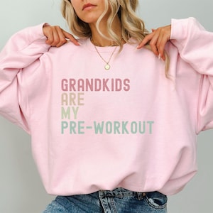 May include: Pink sweatshirt with the text "Grandkids are my pre-workout" in a rainbow gradient.