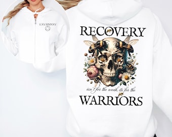 以下が含まれることがあります： 背面に蜂と花に囲まれた人間の頭蓋骨のグラフィックと「RECOVERY isn't for the weak, its for the WARRIORS」という文字がプリントされた白いジップアップパーカー。胸元には「V.XV.MMXXV」という文字と三角形のシンボルがデザインされています。