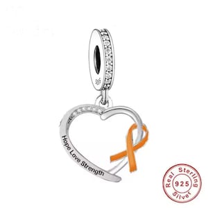 Könnte beinhalten: Ein silberner Charm-Anhänger mit herzförmigem Anhänger. Das Herz trägt die Inschrift "Hope Love Strength" und ein orangefarbenes Band. Der Charm hat eine Schlaufe mit klaren Steinen.