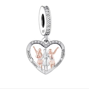 May include: Silver charm with a heart-shaped design featuring three figures holding hands. The heart has the words "Always Sisters Forever Friends" inscribed around it. The charm is adorned with clear cubic zirconia stones.
