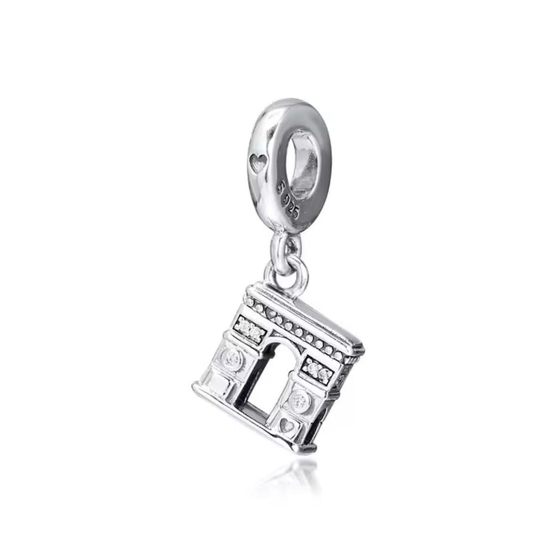 May include: Silver charm featuring a detailed replica of the Arc de Triomphe in Paris, France. The charm has clear cubic zirconia stones and a heart-shaped detail on the bottom.