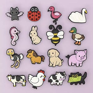 Könnte beinhalten: Eine Sammlung farbenfroher Schuhanhänger mit Tiermotiven, darunter eine Fledermaus, ein Marienkäfer, ein Flamingo, ein Schwan, ein Seepferdchen, ein Kaninchen, eine Biene, eine Ente, ein Strauß, ein Pferd, ein Hund, ein Schwein, eine Kuh, ein Huhn, eine weitere Kuh und eine Katze mit Geld.