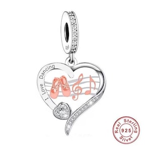 May include: A silver charm in the shape of a heart with a pink ballet shoe design, musical notes, and the text "I Love Dancing". The charm is decorated with clear cubic zirconia stones and has a sterling silver 925 stamp.